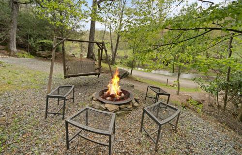 a fire pit with two chairs and a swing at Riverside Mountain Retreat in Boone