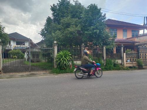 a person riding a motorcycle down the street at Near Central Festival Hat Yai,5-8 people in Hat Yai