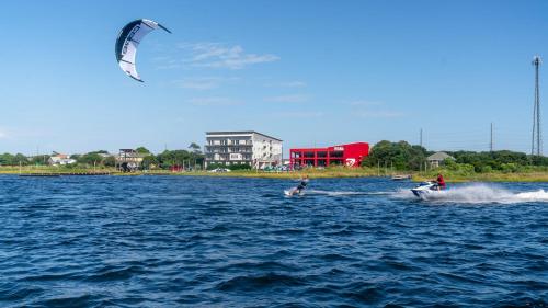 two people are kite surfing in the water at Watermen's Cabana 1B - 2-Bed, 1-Bath Apartment - Walk To BEACH Access & PET Friendly! in Waves