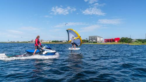 two people are riding on surfboards on the water at Watermen's Cabana 1B - 2-Bed, 1-Bath Apartment - Walk To BEACH Access & PET Friendly! in Waves