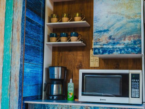 a kitchen counter with a microwave and cups on a shelf at Petra Lago in San Bernardino