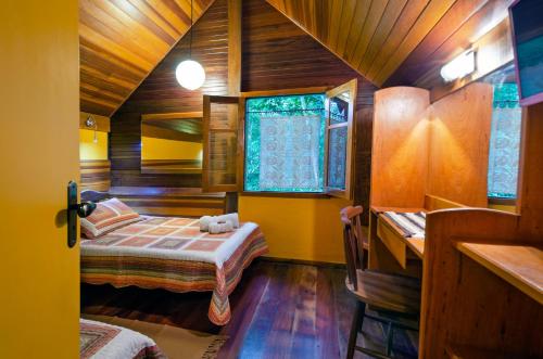 a room with two beds and a desk in it at Pousada Colher de Chá - chalés in Visconde De Maua