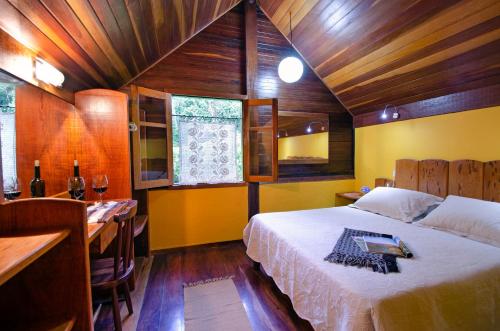 a bedroom with a bed and a table and a desk at Pousada Colher de Chá - chalés in Visconde De Maua