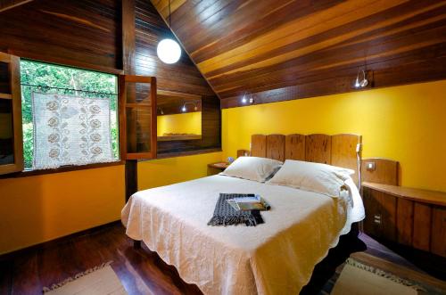 a bedroom with a bed in a room with yellow walls at Pousada Colher de Chá - chalés in Visconde De Maua