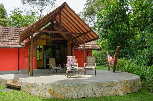a pavilion with a table and chairs in front of a house at Pousada Colher de Chá - chalés in Visconde De Maua
