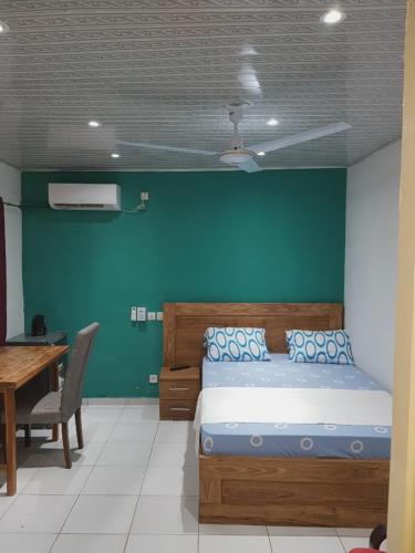 a bedroom with a bed with a green wall at La Résidence in Lomé