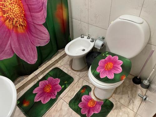 a bathroom with a toilet and a flower shower curtain at El Tata in Puerto Iguazú