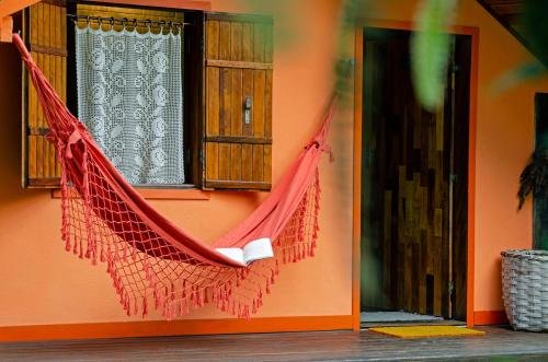 a red hammock hanging from the side of a house at Pousada Colher de Chá - chalés in Visconde De Maua