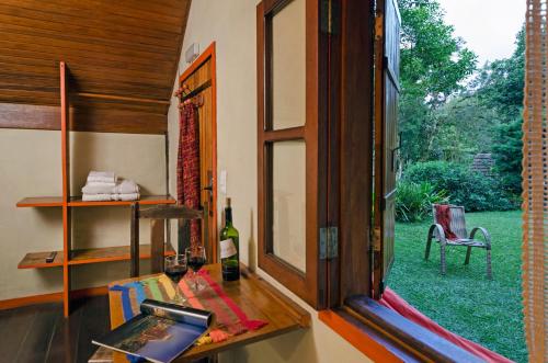 a room with a window and a table with a bottle of wine at Pousada Colher de Chá - chalés in Visconde De Maua