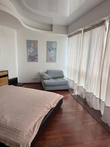 a bedroom with a bed and a couch and curtains at Отдых у моря Одесса in Kryzhanivka