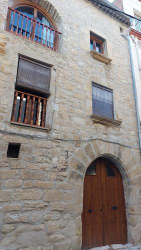 a stone building with a wooden door and two windows at Cal Mitger in Viñaixa