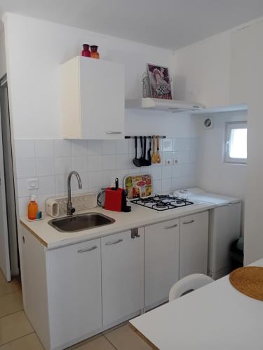 une cuisine blanche avec un évier et une cuisinière dans l'établissement Le studio, à Cavaillon