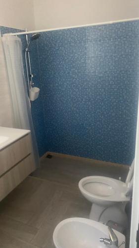 a bathroom with a toilet and a blue tiled wall at Casa Vacanze-Le stanze di Eolo in Marsala