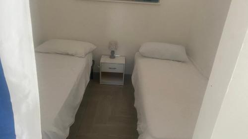 two twin beds in a small room with a night stand at Casa Vacanze-Le stanze di Eolo in Marsala