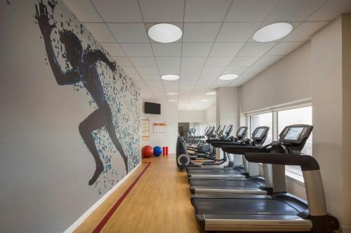 a gym with rows of tread machines in a row at Sheraton LaGuardia East Hotel in Queens