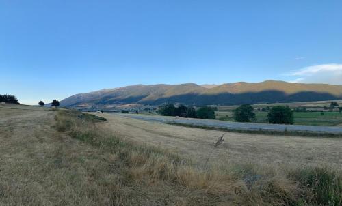 a field with a road and mountains in the background at Les chardons bleus in Formiguères