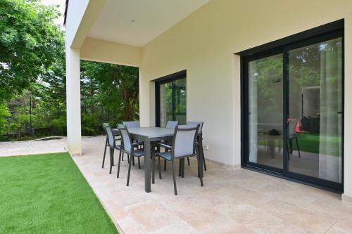 une salle à manger avec une table et des chaises sur un patio dans l'établissement Villa neuve climatisée, avec piscine - 15 mn d'Uzès et du Pont du Gard, à Blauzac