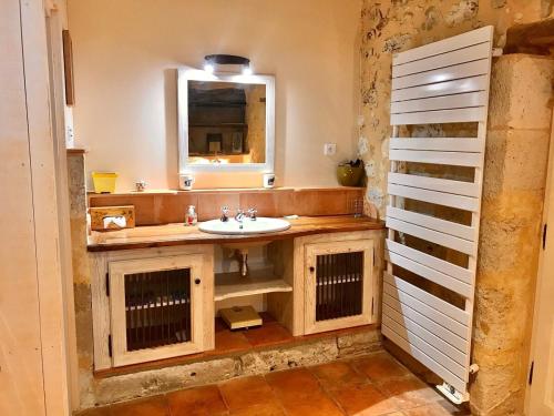 une salle de bain avec un lavabo et un miroir dans l'établissement Large country cottage, à Lusignan-Petit
