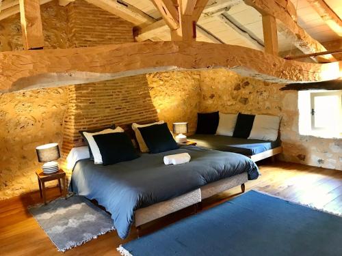 une chambre avec un grand lit dans un mur de pierre dans l'établissement Large country cottage, à Lusignan-Petit