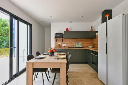 une cuisine avec une table en bois et une cuisine avec des armoires vertes dans l'établissement Villa neuve climatisée, avec piscine - 15 mn d'Uzès et du Pont du Gard, à Blauzac