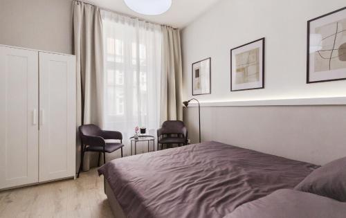 a bedroom with a bed and two chairs and a window at Luxury Apartment Kościuszki 9 - Apartament Larcia in Katowice