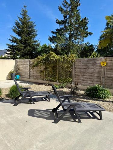 two picnic chairs sitting on a sidewalk next to a fence at Gîte de Kergalet in Pléguien