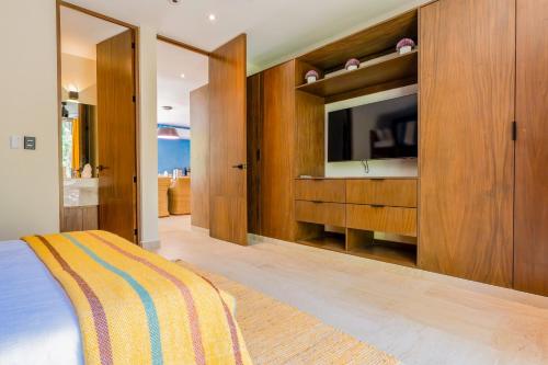 a bedroom with a tv and a bed and wooden cabinets at Casa Jaguar in Xpu Ha