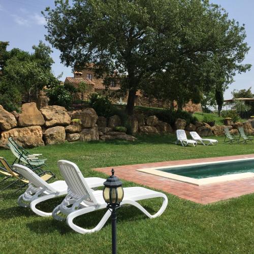 a group of chairs sitting next to a swimming pool at Villa Fonte all'Oppio con area piscina recintata in Pienza