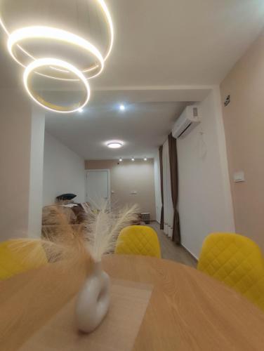a dining room with a table and yellow chairs at Vila Ideal New in Donji Štoj