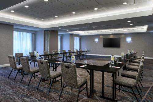 a conference room with tables and chairs and a screen at Washington Dulles Marriott Suites in Herndon