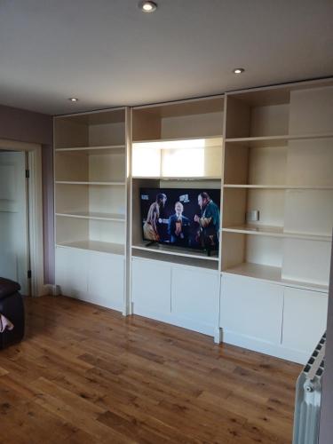 a living room with a tv and shelves at shiv's comfy apartment in Balnacart