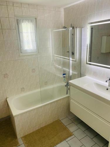 une salle de bain blanche avec une baignoire et un lavabo dans l'établissement Maison familiale - Jardin - Parking - Wifi, à Pithiviers