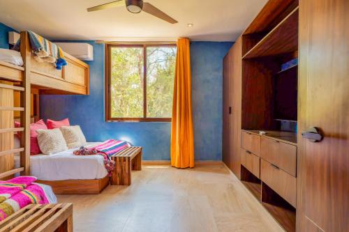 a bedroom with a bed and a tv and a window at Casa Jaguar in Xpu Ha