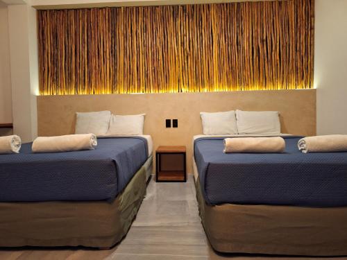 two beds in a hotel room with a wall at Hotel VSI in Playa del Carmen