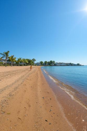 a dog walking on a sandy beach next to the water at Family Home Pool HotTub Near Lighthouse Point Park in New Haven