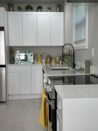 a white kitchen with white cabinets and a sink at Family Home Pool HotTub Near Lighthouse Point Park in New Haven