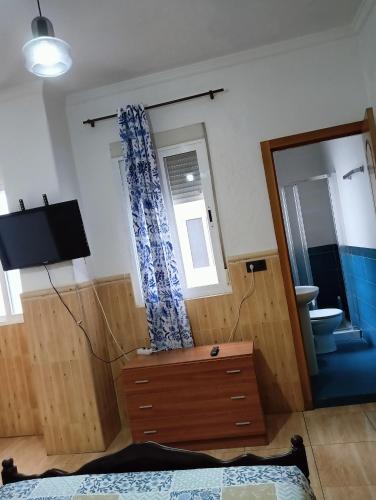 a bedroom with a bed and a dresser and a mirror at Pensión Antequera in Melilla