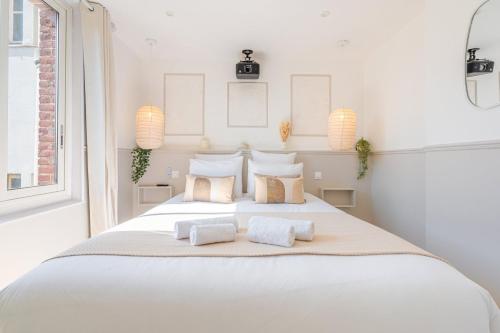 une chambre blanche avec un grand lit blanc avec des oreillers dans l'établissement La Suite des Sables, à Houlgate