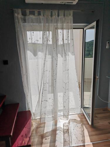 a window with a white curtain and a wooden floor at Holiday House ''Villa Flora'' in Šibenik