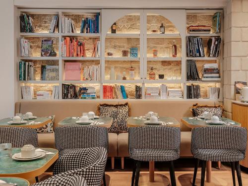 a restaurant with two tables and chairs and books at Hôtel Zélie in Paris