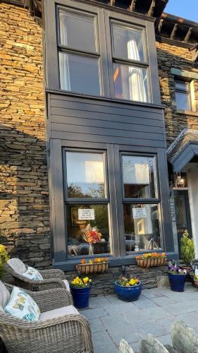 a building with two chairs and windows with flowers at Autumn Leaves Guest House in Windermere
