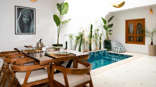 a dining room with a table and chairs and a swimming pool at Riad Reflet D'orient Marrakech in Marrakech