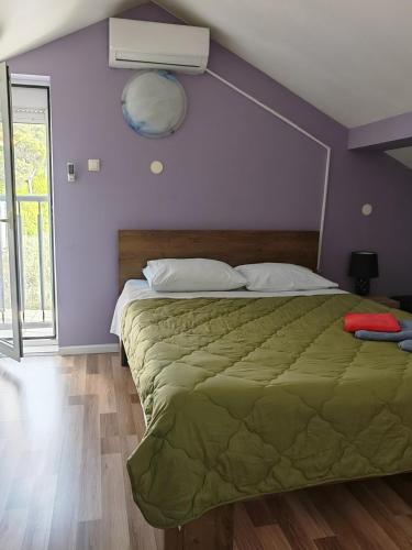 a bedroom with a bed with a green comforter at Holiday House ''Villa Flora'' in Šibenik