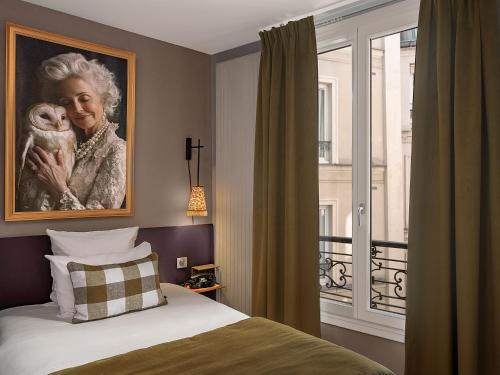 a bedroom with a painting of a woman holding a baby at Hôtel Zélie in Paris