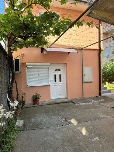 una casa rosa con una porta bianca e un albero di Prestige 4 a Podgorica