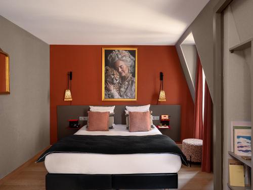 a bedroom with a king sized bed with orange walls at Hôtel Zélie in Paris