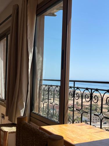 a room with a window with a table and a balcony at SurfAppart Morocco in Tamraght Ouzdar