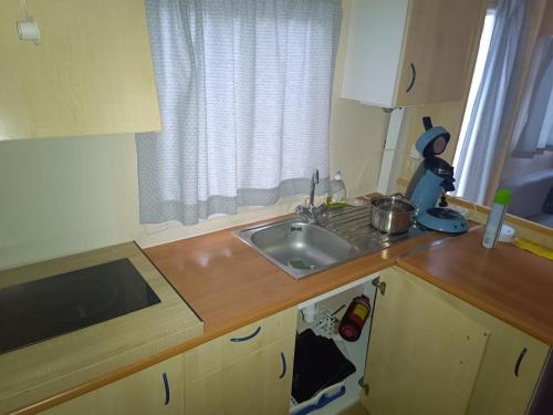une petite cuisine avec un évier et une fenêtre dans l'établissement Camping Les Embruns N2, au Grau-dʼAgde