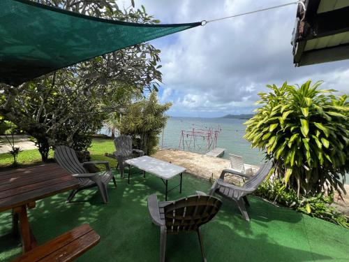 a patio with chairs and a table and the water at VILLA DE LA BAIE RAIATEA - Bord de mer in Uturoa