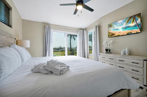 a bedroom with a white bed with a ceiling fan at Villa with Beach Front Views in Cocoa Beach